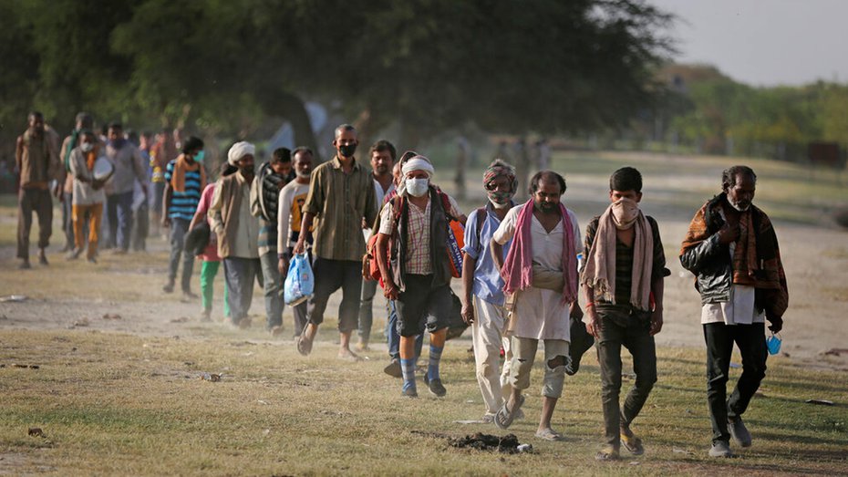 Indian migrant laborers and homeless people walk towards a bus as they are being evicted from the banks of Yamuna River where they have been squatting during lockdown in New Delhi, Wednesday, April 15, 2020.